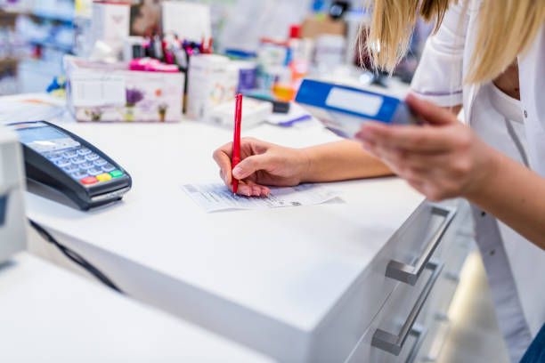 Medicine, pharmaceutics, health care and people concept.  Prescription for medicine in the drugstore. Closeup hand of woman pharmacist with prescription and medicine at drugstore